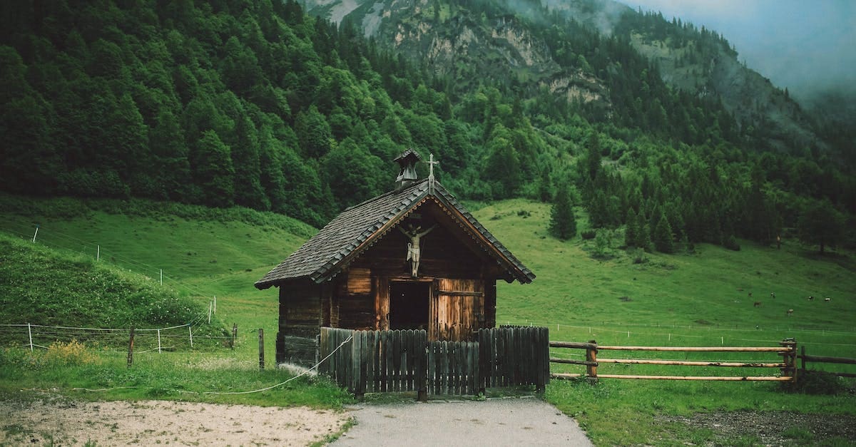 A small wooden chapel with a cross on top, surrounded by trees and grass.