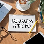 A notebook with the phrase 'Preparation Is The Key' written in bold letters on a wooden table.