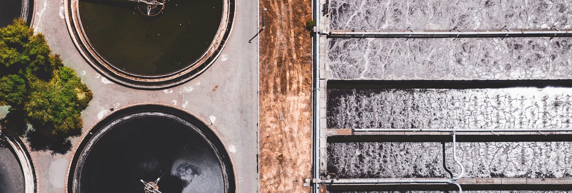 Aerial view of circular wastewater treatment tanks and rectangular filtration areas at a treatment facility.