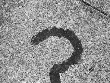 Black question mark stain on a gray concrete surface.
