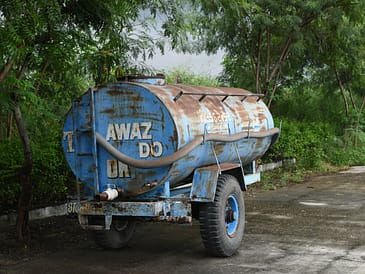 a large blue truck parked next to a lush green forest