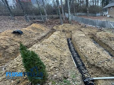 Excavated area showing septic tank installation with pipes and soil in a residential yard.