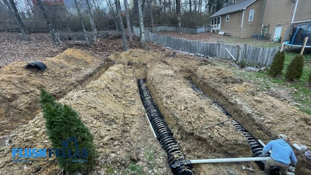 Excavated area showing septic tank installation with pipes and soil in a residential yard.