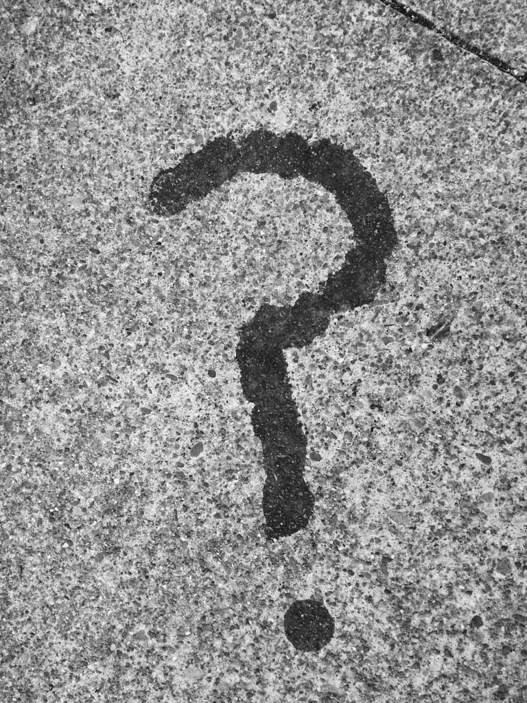 Black question mark stain on a gray concrete surface.